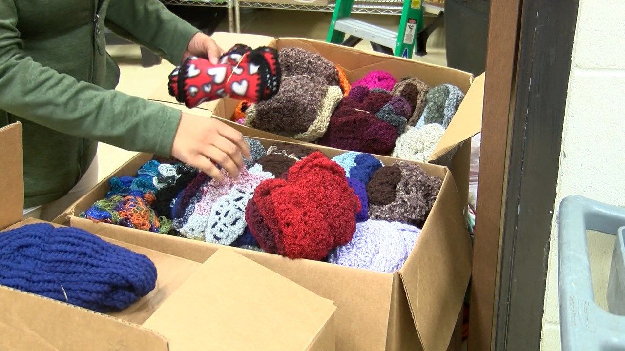 Local food bank volunteer donating handknitted items for people in